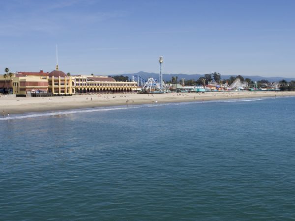 The image shows a beachfront with a large building and amusement park attractions, including a roller coaster, next to the calm ocean water ending the sentence.