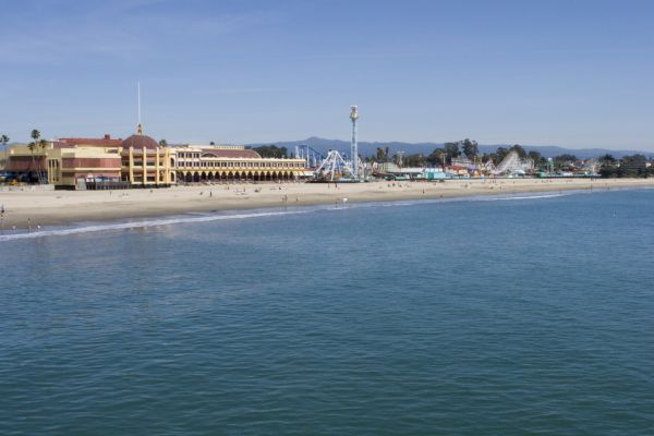 The image shows a beachfront with a large building and amusement park attractions, including a roller coaster, next to the calm ocean water ending the sentence.