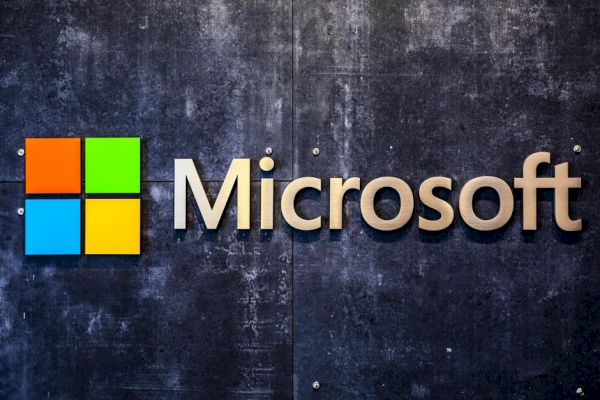 The image displays the Microsoft logo with a colorful square graphic on the left and the word "Microsoft" in clear, modern font on a textured dark background.