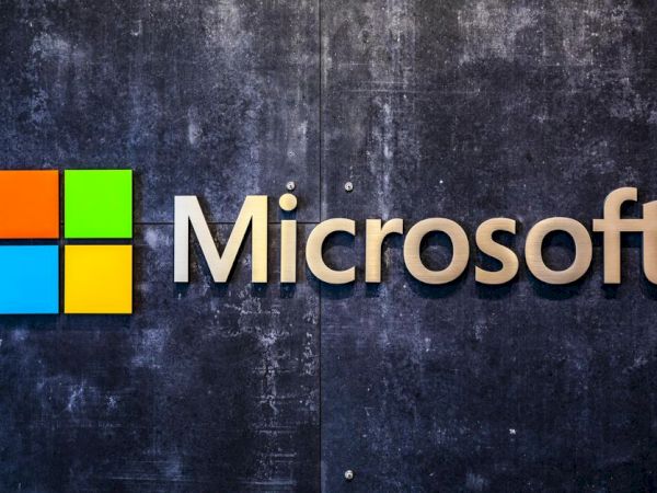 The image displays the Microsoft logo with a colorful square graphic on the left and the word "Microsoft" in clear, modern font on a textured dark background.