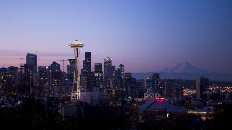 This image showcases the Seattle skyline at dusk, featuring the Space Needle and various skyscrapers, with Mount Rainier visible in the background.